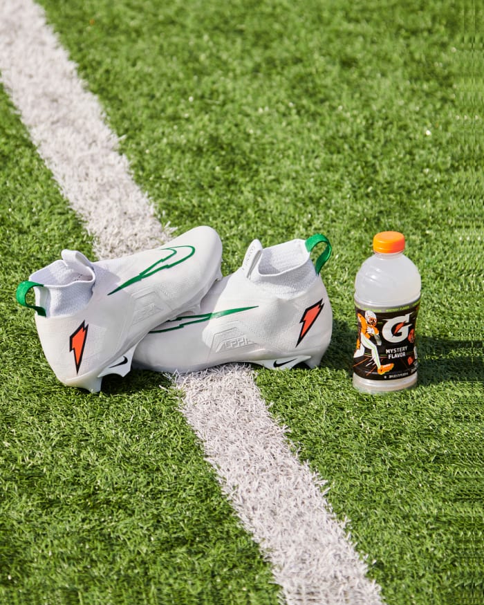 Shedeur Sanders' white and green Nike cleats next to a Gatorade bottle.